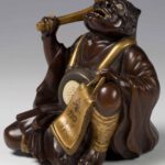 A FINELY CARVED JAPANESE HARDWOOD AND GOLD LACQUER ONI OKIMONO