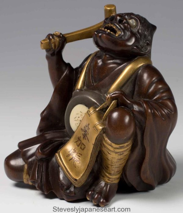 A FINELY CARVED JAPANESE HARDWOOD AND GOLD LACQUER ONI OKIMONO