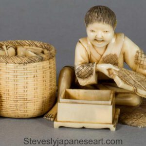 A FUN JAPANESE IVORY OKIMONO OF A BOY WITH HIS TOYS