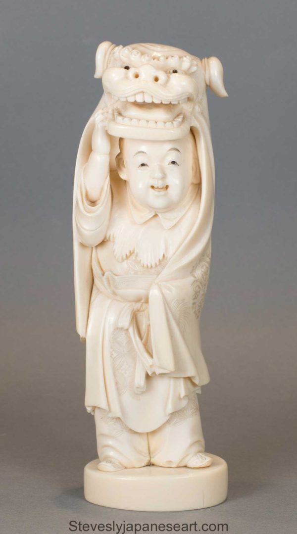A CHARMING JAPANESE IVORY OKIMONO OF A BOY PERFORMING A LION DANCE