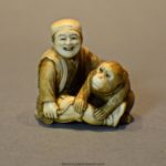 A CHARMING JAPANESE IVORY OKIMONO OF A SEATED MONKEY & SARUMAWASHI- SIGNED